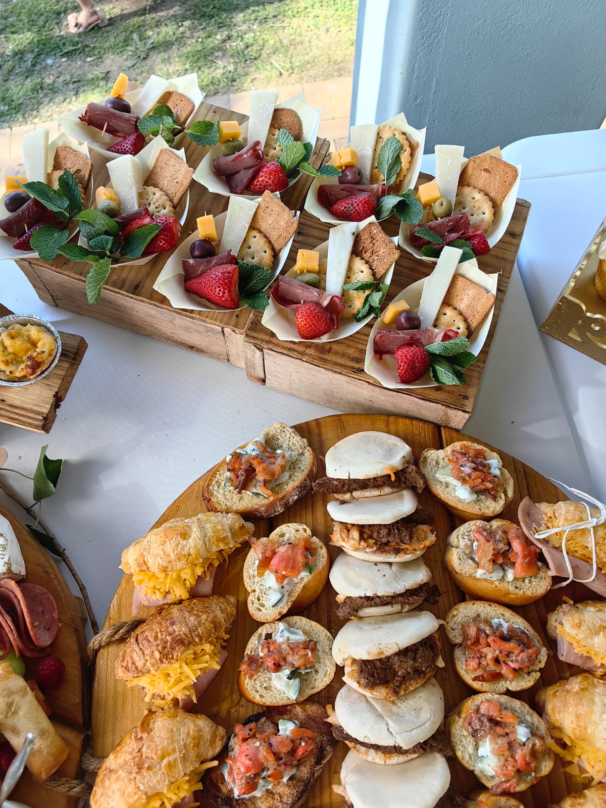 Catering by Creations: individual boats of dried meat, cheese, crackers, olives and strawberries beside a platter of mini croissants, bruschetta and sliders