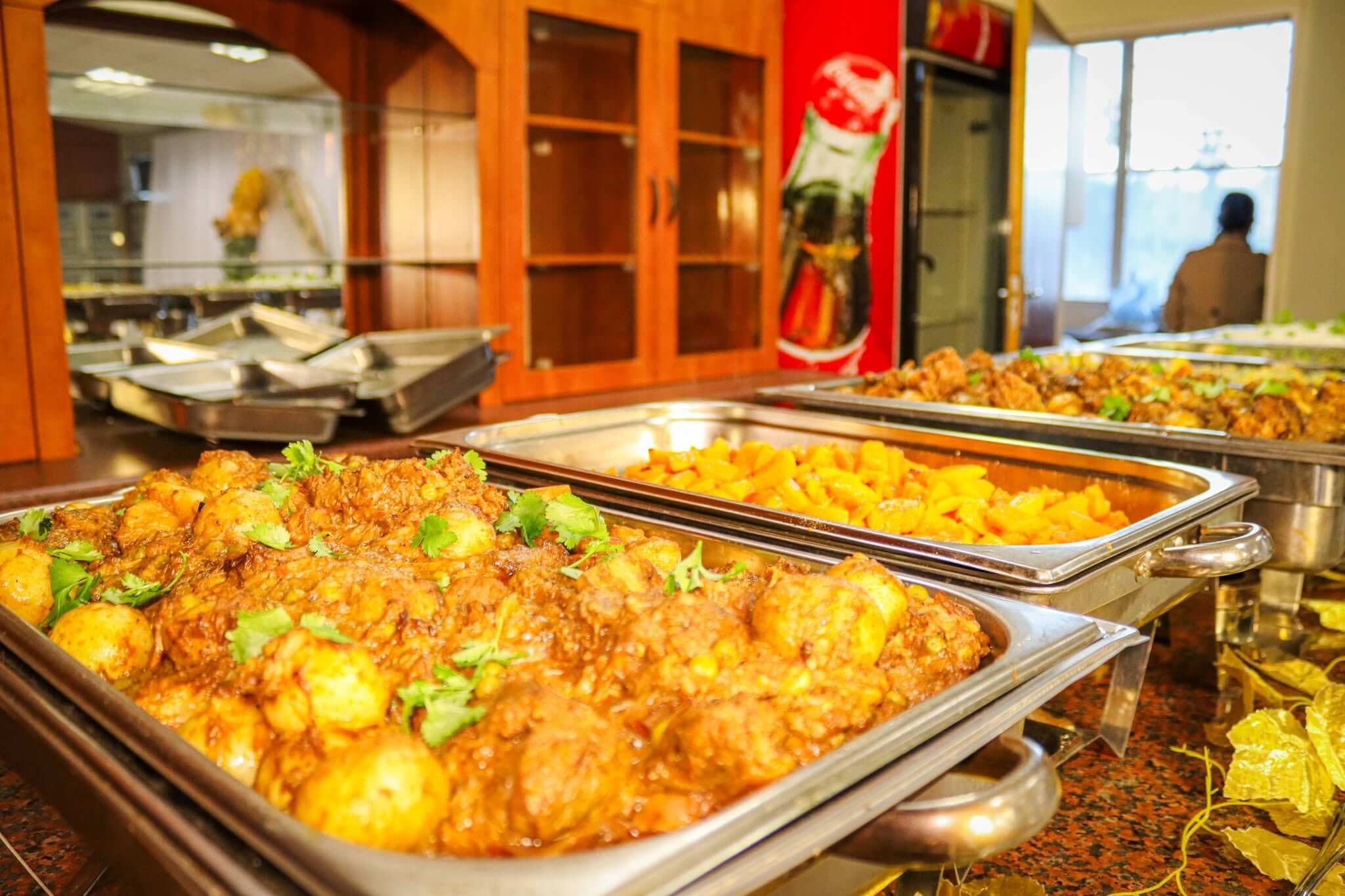 Buffet catering by Creations: chafing dishes of potato and chicken curry garnished with coriander, roasted butternut and a meat dish