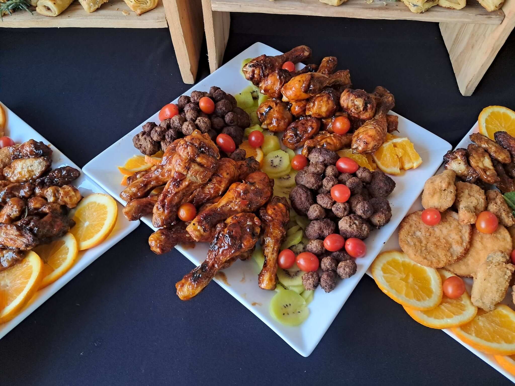 Finger food platters by Creations catering: sticky chicken drumsticks, meatballs, crumbed chicken and cherry tomatoes with orange and kiwi slices