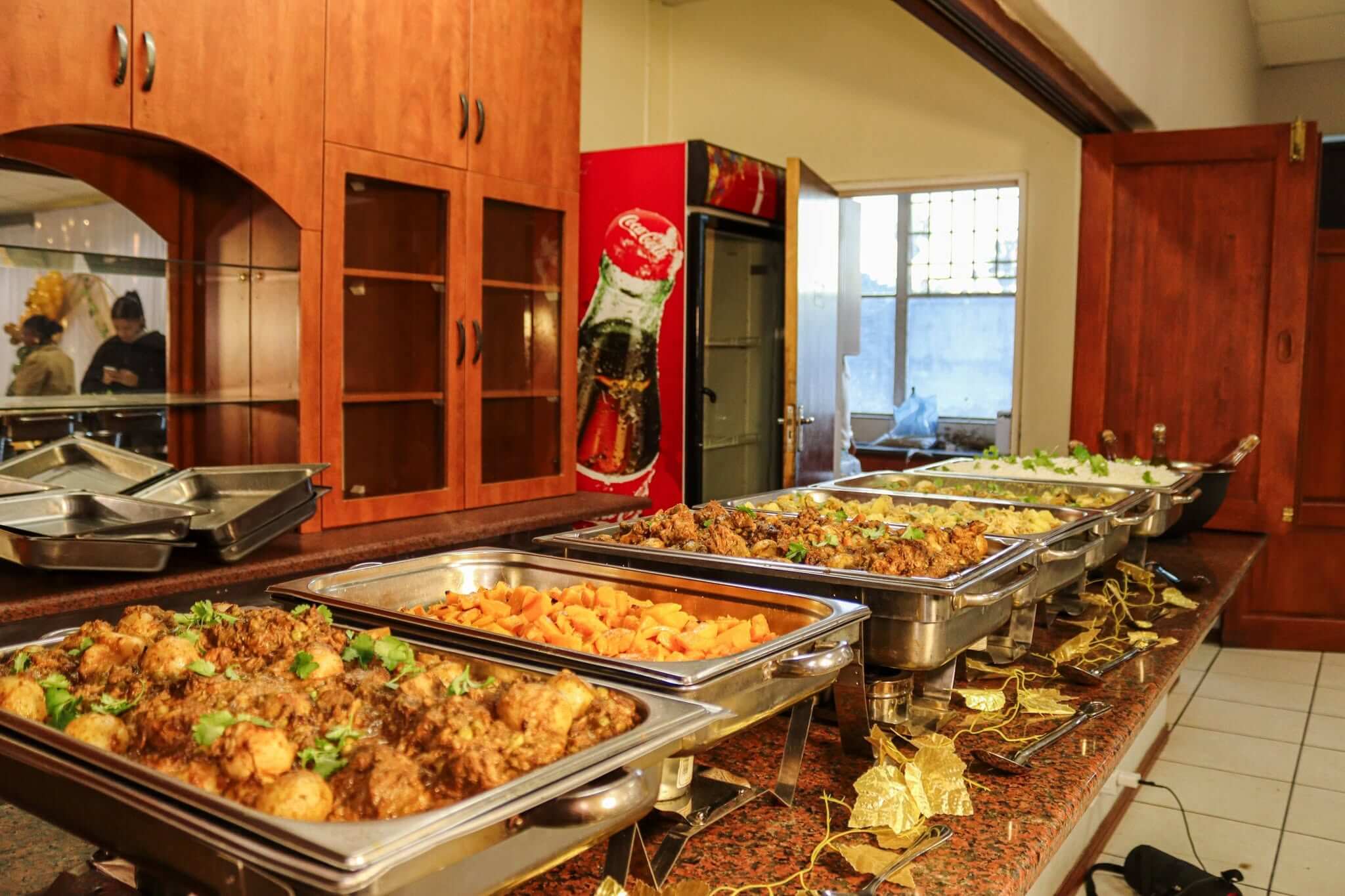 Full buffet line by Creations catering: a row of silver chafing dishes with curries, roasted butternut, rice and gold leaf table decor
